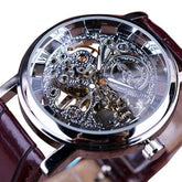 Skeleton dial mechanical watch with silver case, visible gears, and brown leather strap