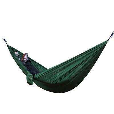 Green nylon hammock with person lying inside, relaxed fit, outdoor lifestyle accessory