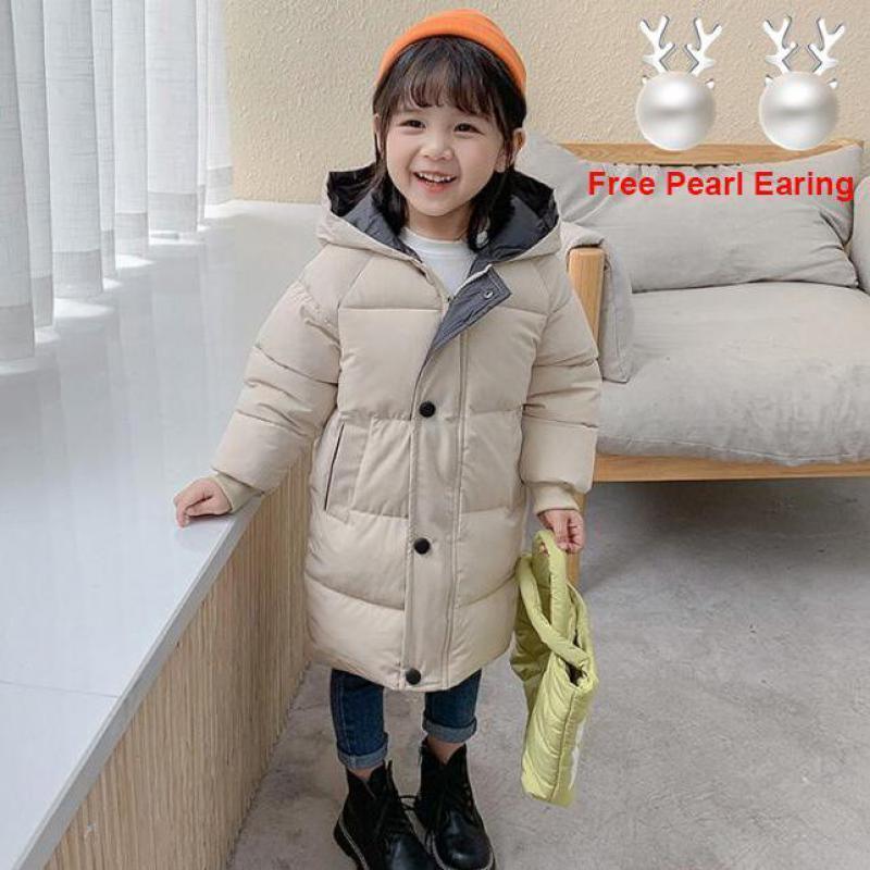 Kid wearing a beige long padded winter coat, orange beanie, dark jeans, and black boots.