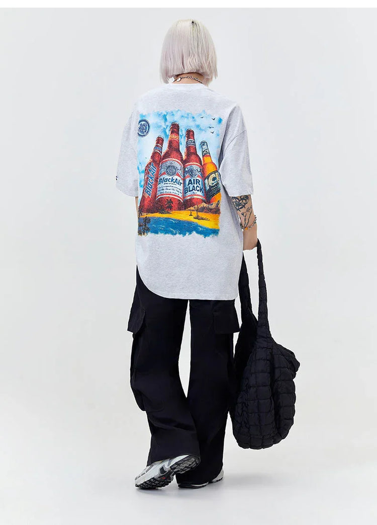 Oversized grey graphic t-shirt with bottle print, black cargo pants, relaxed streetwear style
