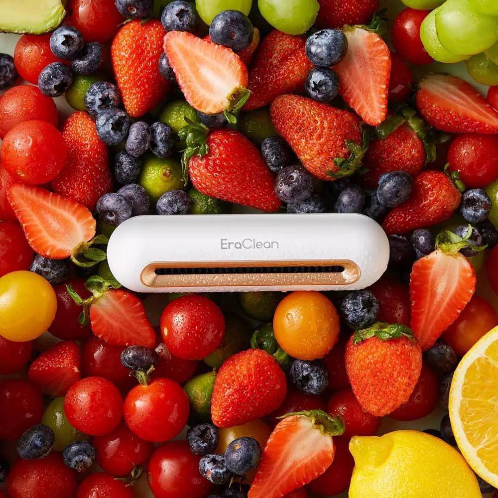 White electronic cleaner device on assorted fresh strawberries, blueberries, and citrus fruits