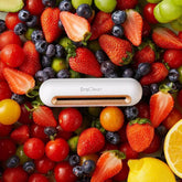 White electronic cleaner device on assorted fresh strawberries, blueberries, and citrus fruits