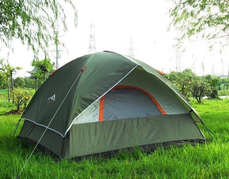 Green dome camping tent with orange trim set up on grassy field outdoors