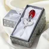 Silver metal rose with red crystal bud in gift box on satin fabric