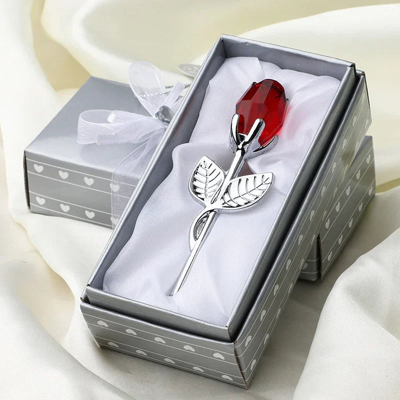 Silver metal rose with red crystal bud in gift box on satin fabric