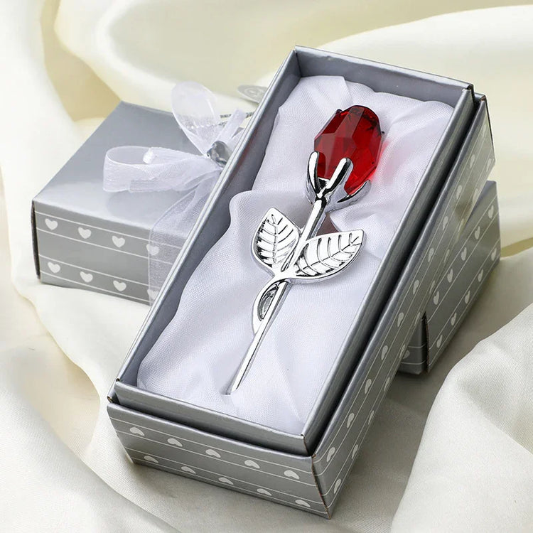 Silver metal rose with red crystal bud in gift box on satin fabric