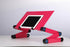 Adjustable pink metal laptop stand with folding legs and tablet holder on white desk