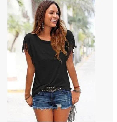 Woman wearing black fringed short-sleeve top and distressed denim shorts outdoors