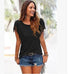 Woman wearing black fringed short-sleeve top and distressed denim shorts outdoors