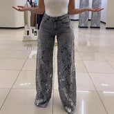 Woman wearing high-waisted grey wide-leg jeans with floral lace cutout design, paired with a white sleeveless top.
