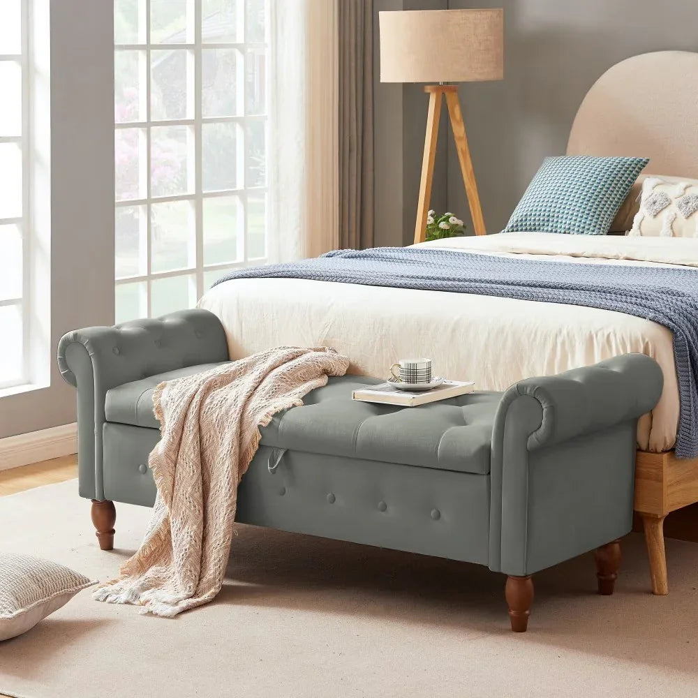 Gray tufted upholstered storage bench with rolled arms at foot of modern bed