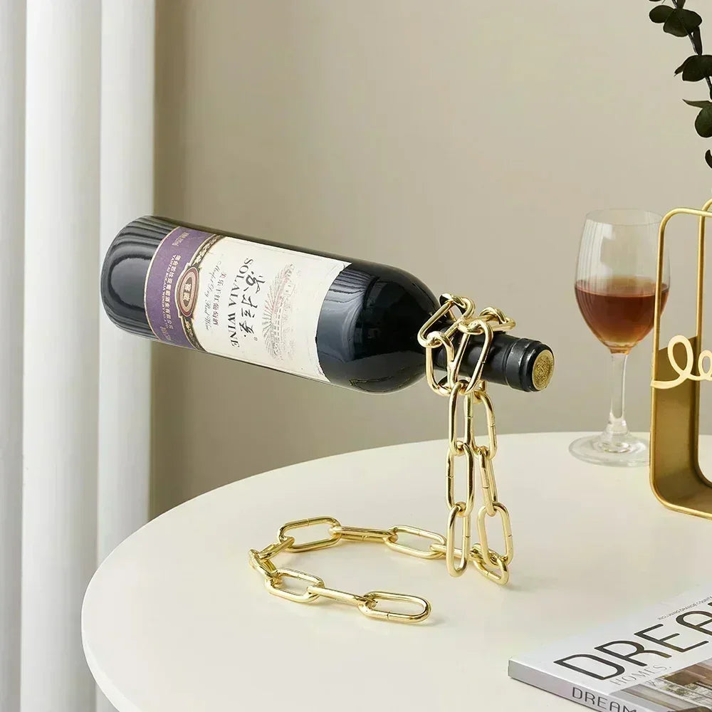 Gold chain wine bottle holder on white table with red wine glass, modern decor