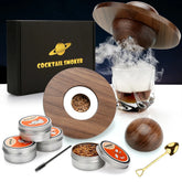 Modern cocktail smoker kit with wood chips, metal tins, glass of whiskey, and wooden lid.