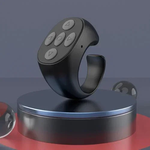 Black smart ring with circular control buttons, modern tech accessory displayed on a pedestal.