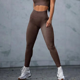Woman wearing brown high-waisted seamless leggings and crop top, fitted athletic style