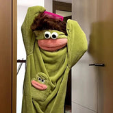Person wearing green plush frog-themed hooded towel with cartoon eyes and soft material
