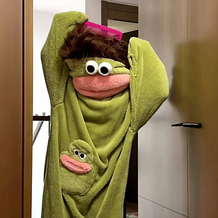 Person wearing green plush frog-themed hooded towel with cartoon eyes and soft material