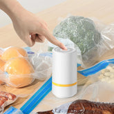 Hand using a white vacuum sealer on sealed food bags for fresh food storage