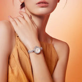 Woman in sleeveless mustard-brown dress wearing sleeveless, loose-fit style, with a silver watch.