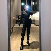 Woman wearing black utility jumpsuit with zip front and combat boots, streetwear style