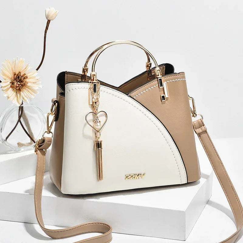 Beige and white faux leather crossbody bag with gold hardware and heart tassel charm, modern fit
