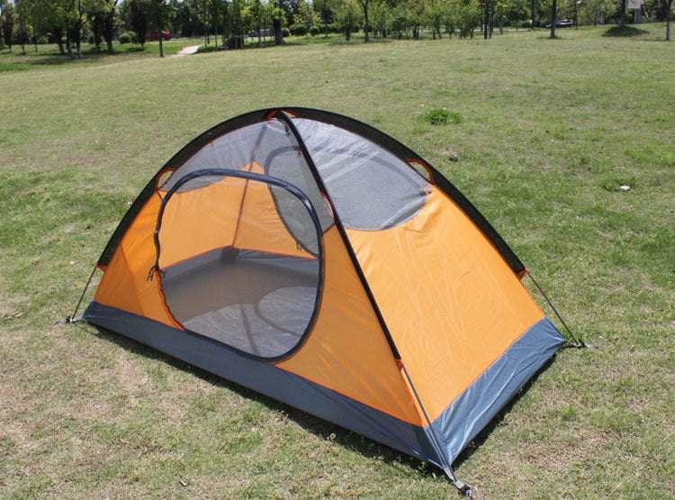 Orange and grey dome tent with mesh panels set up on grassy field, lightweight camping gear