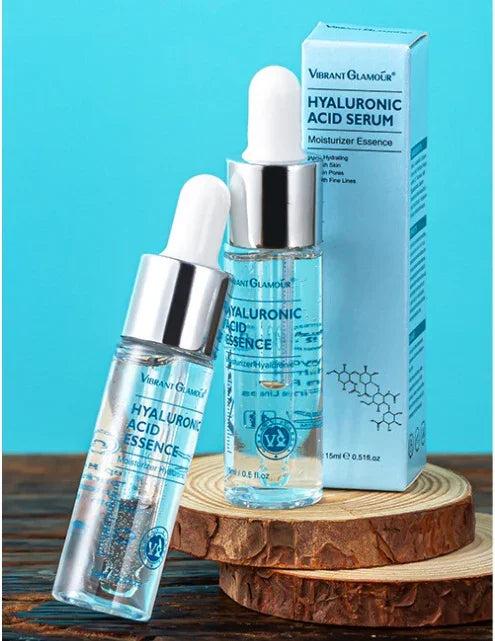 Clear hyaluronic acid serum bottles with dropper caps on wooden slices, blue background.