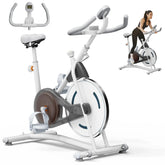 Woman wearing black fitted athletic wear using a white stationary exercise bike indoors.