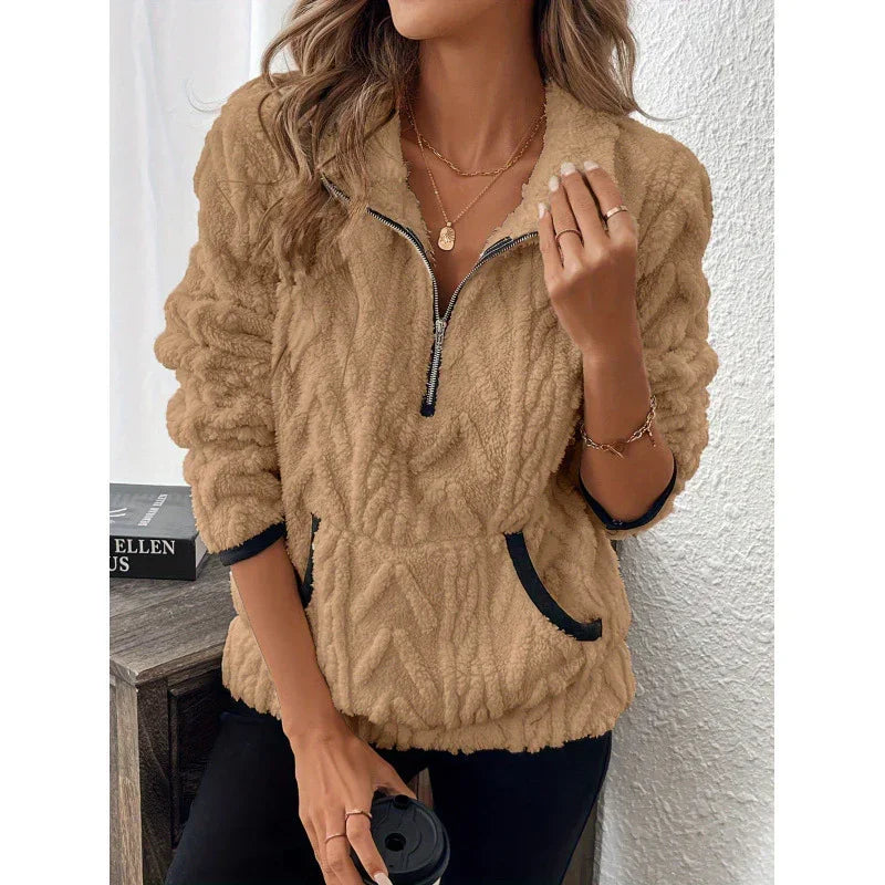 Woman wearing a tan fleece pullover with zip collar, relaxed fit, and black trim details.