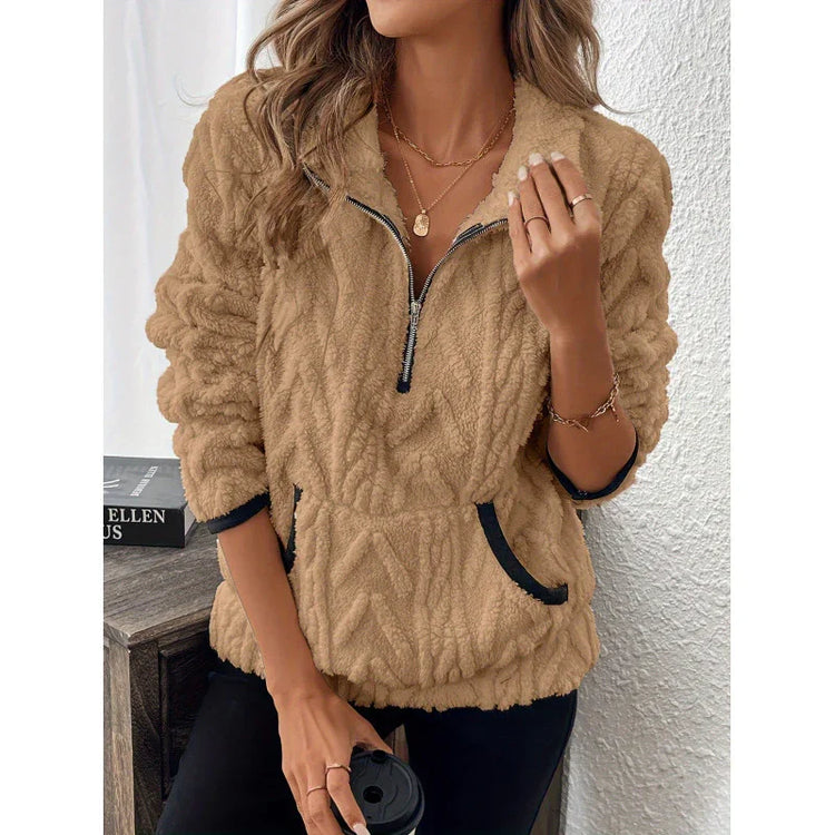 Woman wearing a tan fleece pullover with zip collar, relaxed fit, and black trim details.
