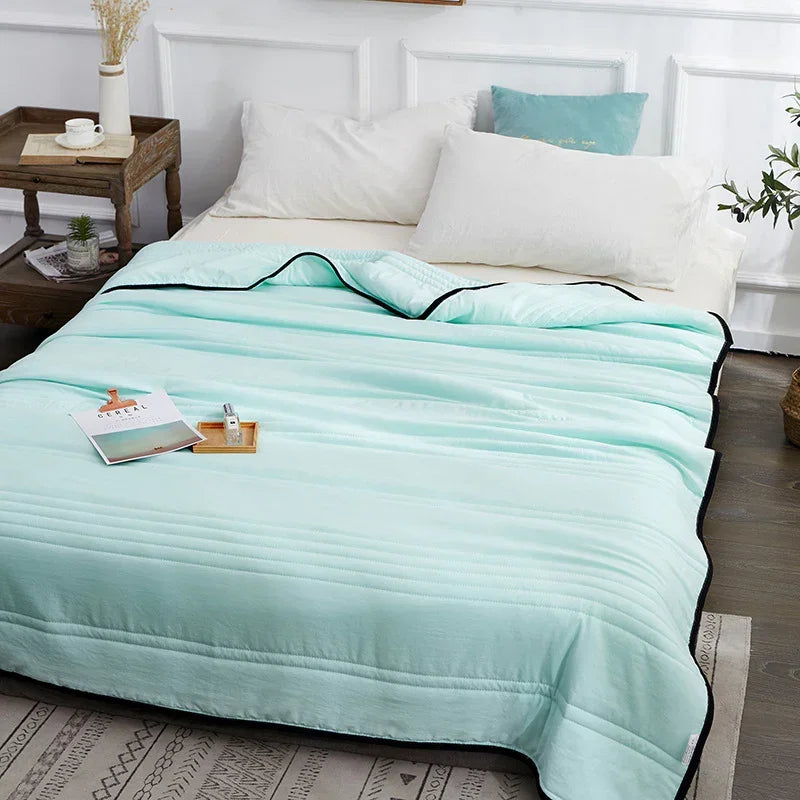 Light blue quilted comforter with black trim, soft fabric, on a modern neatly made bed