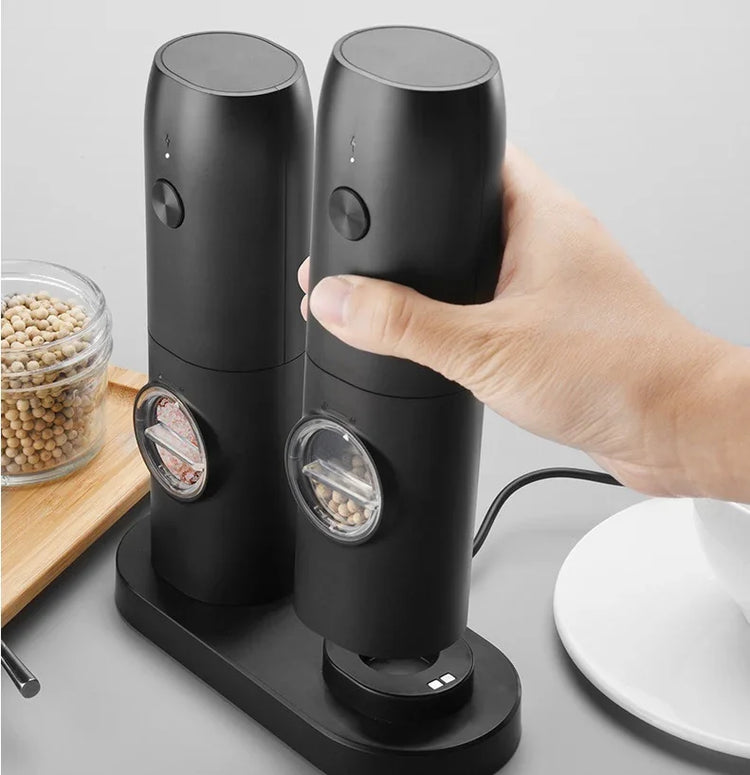 Set of sleek black electric salt and pepper grinders on charging base, modern kitchen accessory