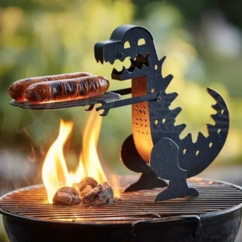 Black metal dinosaur-shaped grill accessory holding sausages over charcoal barbecue flames