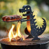 Dinosaur-shaped metal grill accessory holding sausages over open flame on barbecue
