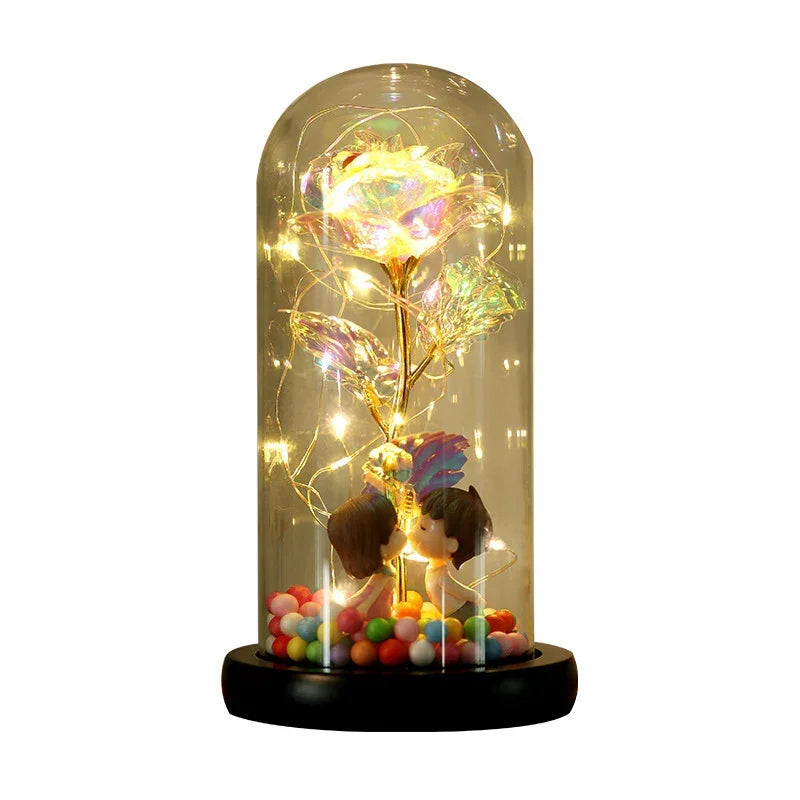 Glass dome with LED-lit iridescent artificial rose and kissing figurines on colorful beads