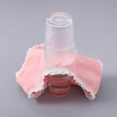 Pink cotton underwear with white lace trim, soft material, displayed over two glasses