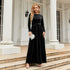 Woman wearing a black velvet long-sleeve maxi dress with a tie waist, elegant fit