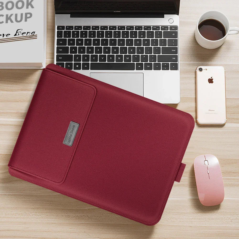 Burgundy faux leather laptop sleeve with slim fit on a wooden desk near a laptop and accessories
