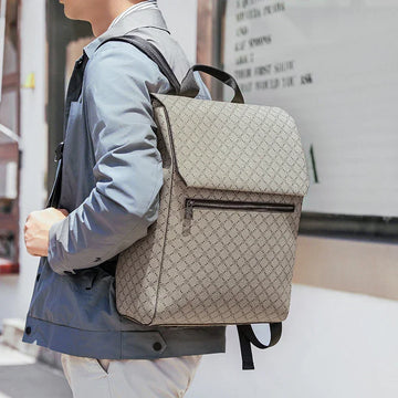 Man wearing a light gray patterned jacket and large beige textured backpack, modern fit