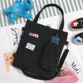 Black canvas tote bag with pockets, adjustable strap, casual streetwear style, relaxed fit