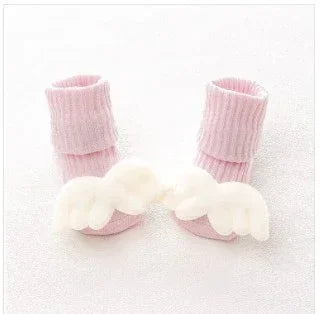 Soft pink ribbed baby socks with white plush angel wings, cozy and cute style for infants