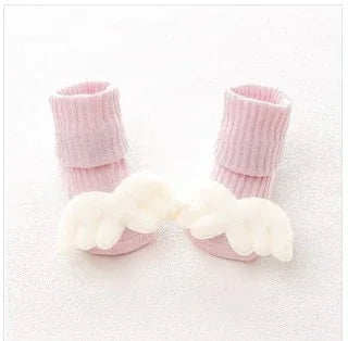 Soft pink ribbed baby socks with white plush angel wings, cozy and cute style for infants