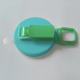 Blue and green plastic clip with round base and handle on a white surface