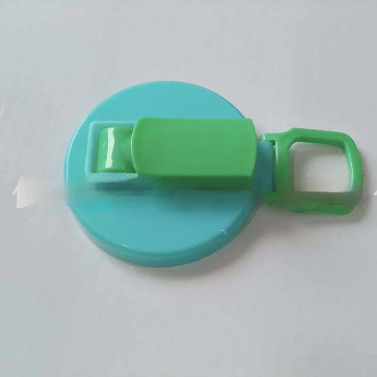 Blue and green plastic clip with round base and handle on a white surface