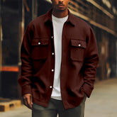 Man wearing oversized brown corduroy shirt jacket with front pockets over white tee, relaxed fit.