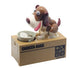 Brown and white plastic coin bank dog toy with a movable head and coin bowl on a tan box.
