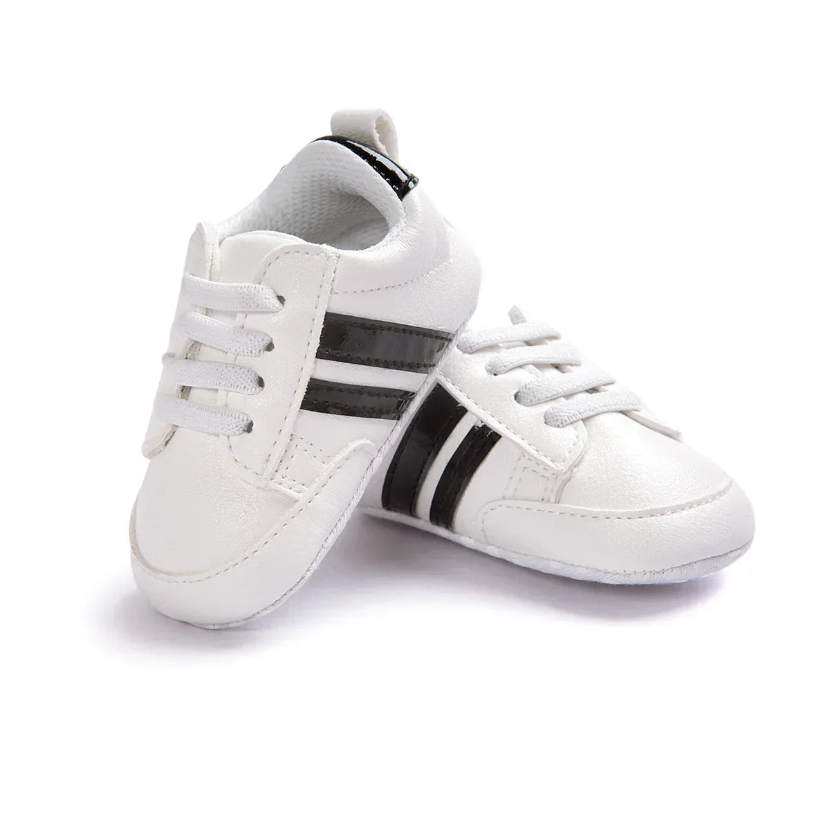 White baby sneakers with black stripes, faux leather upper, lace-up style, soft sole