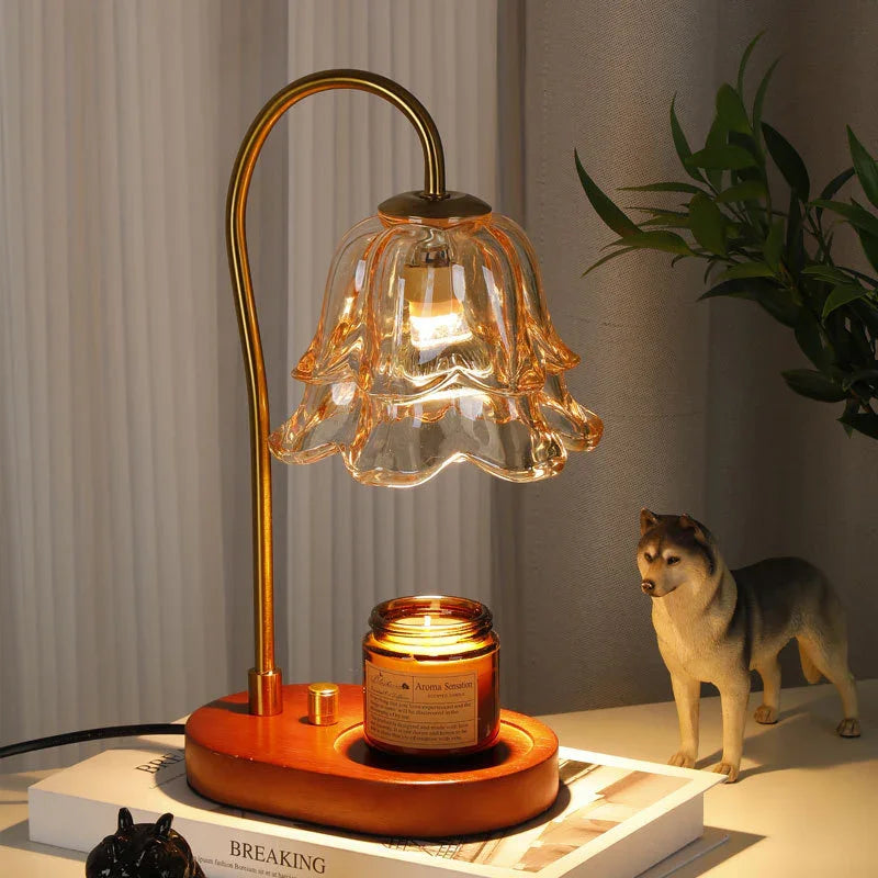 Elegant gold and glass flower-shaped table lamp with wooden base, lit candle, and cozy decor