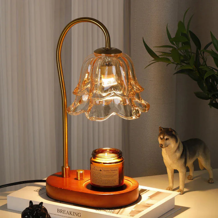 Elegant gold and glass flower-shaped table lamp with wooden base, lit candle, and cozy decor