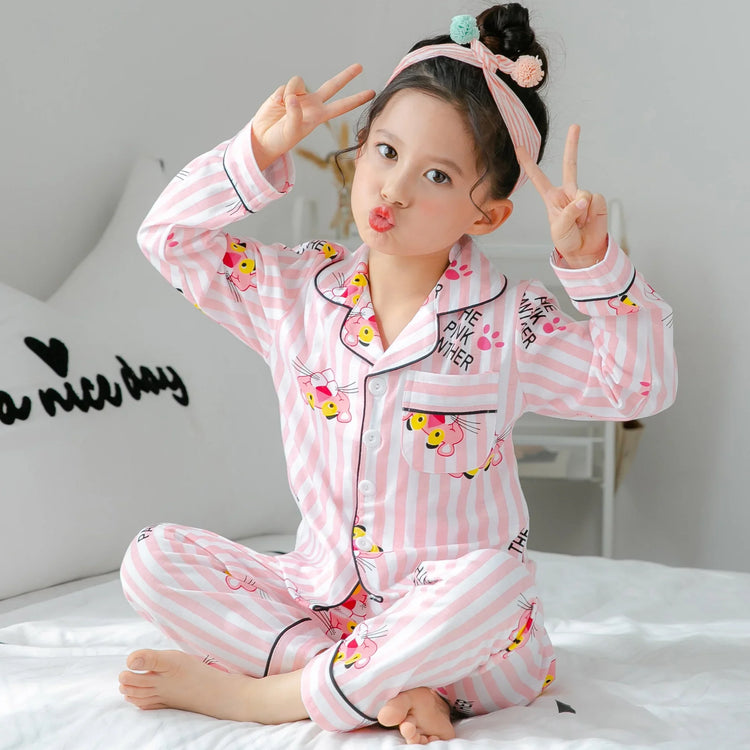 Child in pink striped cotton pajamas with cartoon print and relaxed fit, sitting on bed